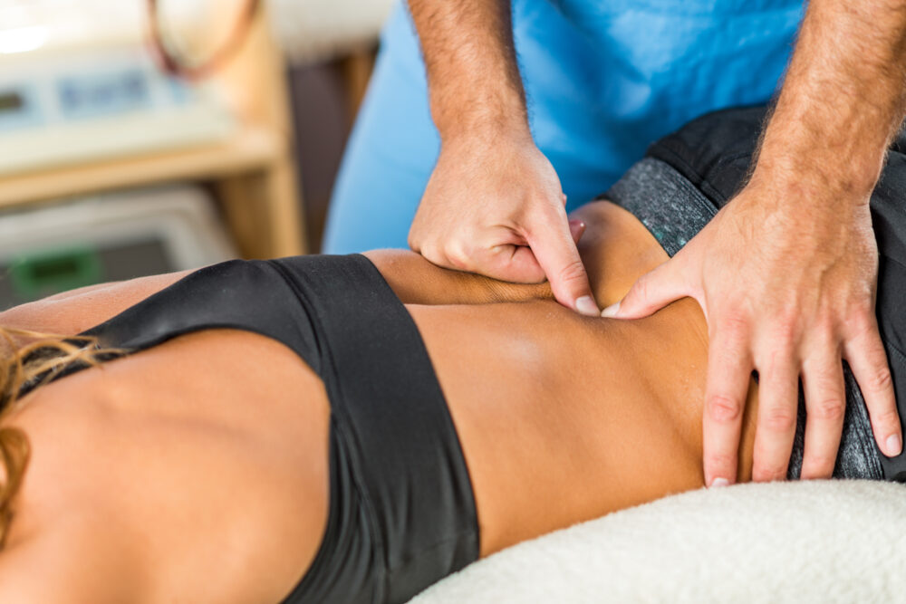 triumph physio clinician treating a patient's back with their hands