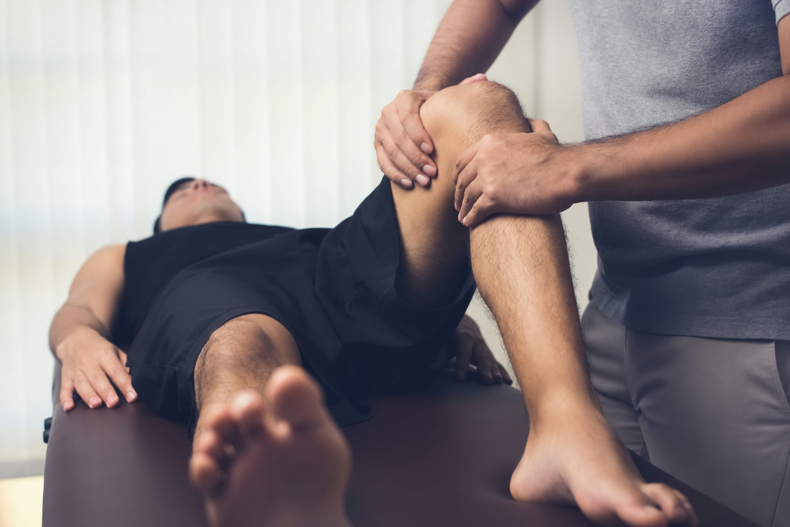 Physio assessing the knee of a patient