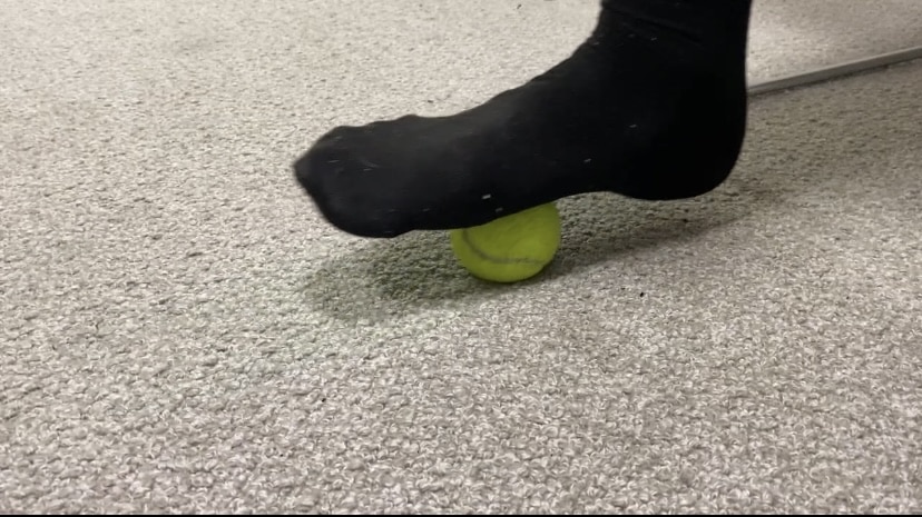 showing patients to massage ball underneath the foot to relieve plantar fascia pain