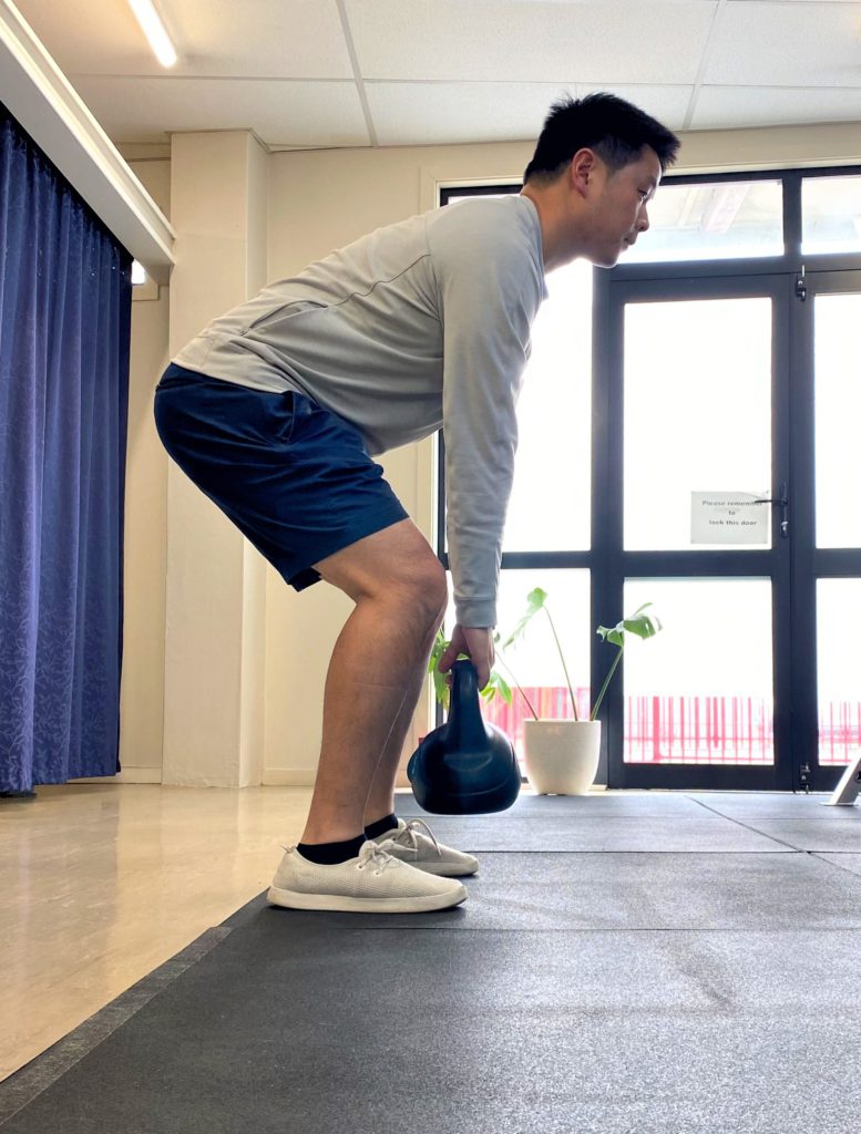 physio showing how to deadlift with kettlebell